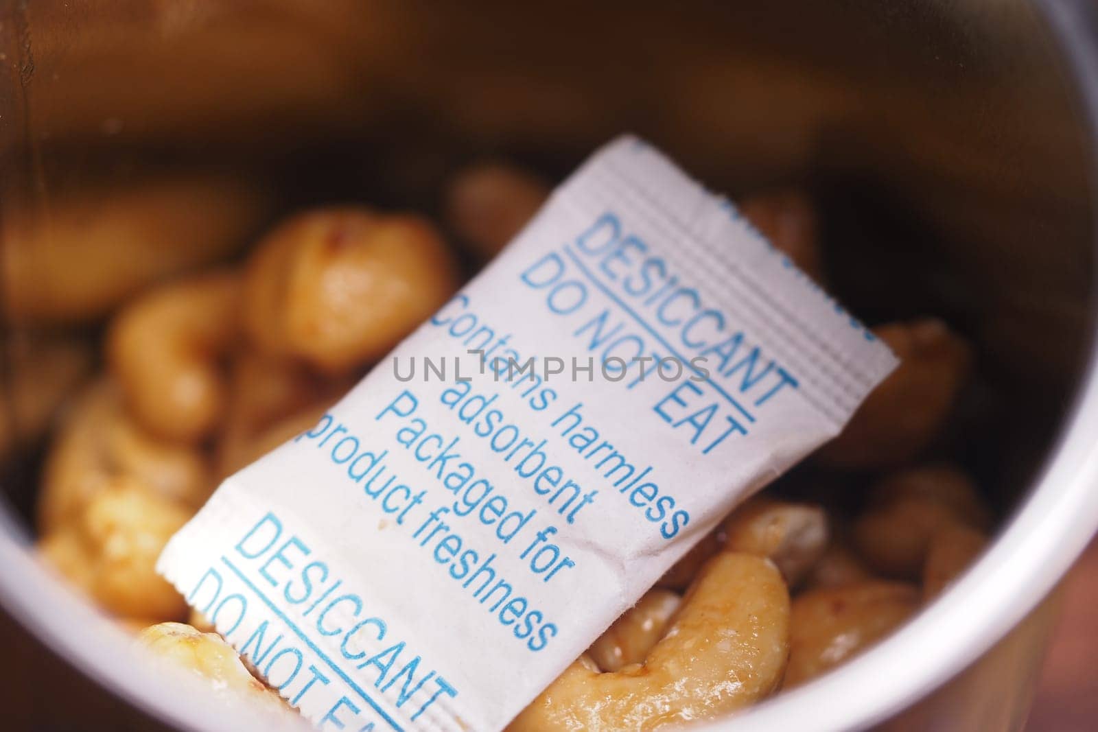Cashew nuts are stored in a container with a desiccant packet for freshness.