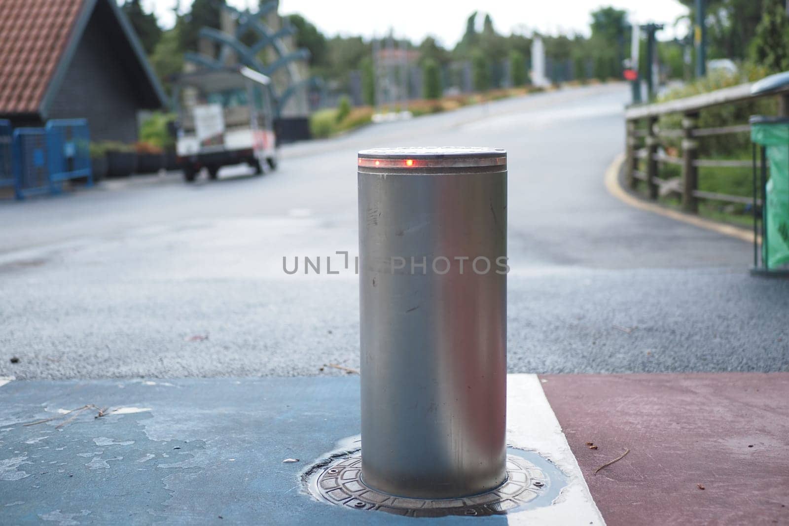 A metal barrier sits on a vibrant pavement in a tranquil park area.