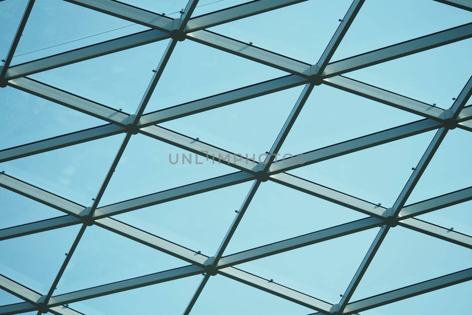 A geometric glass ceiling showcases a blue sky above, highlighting design.