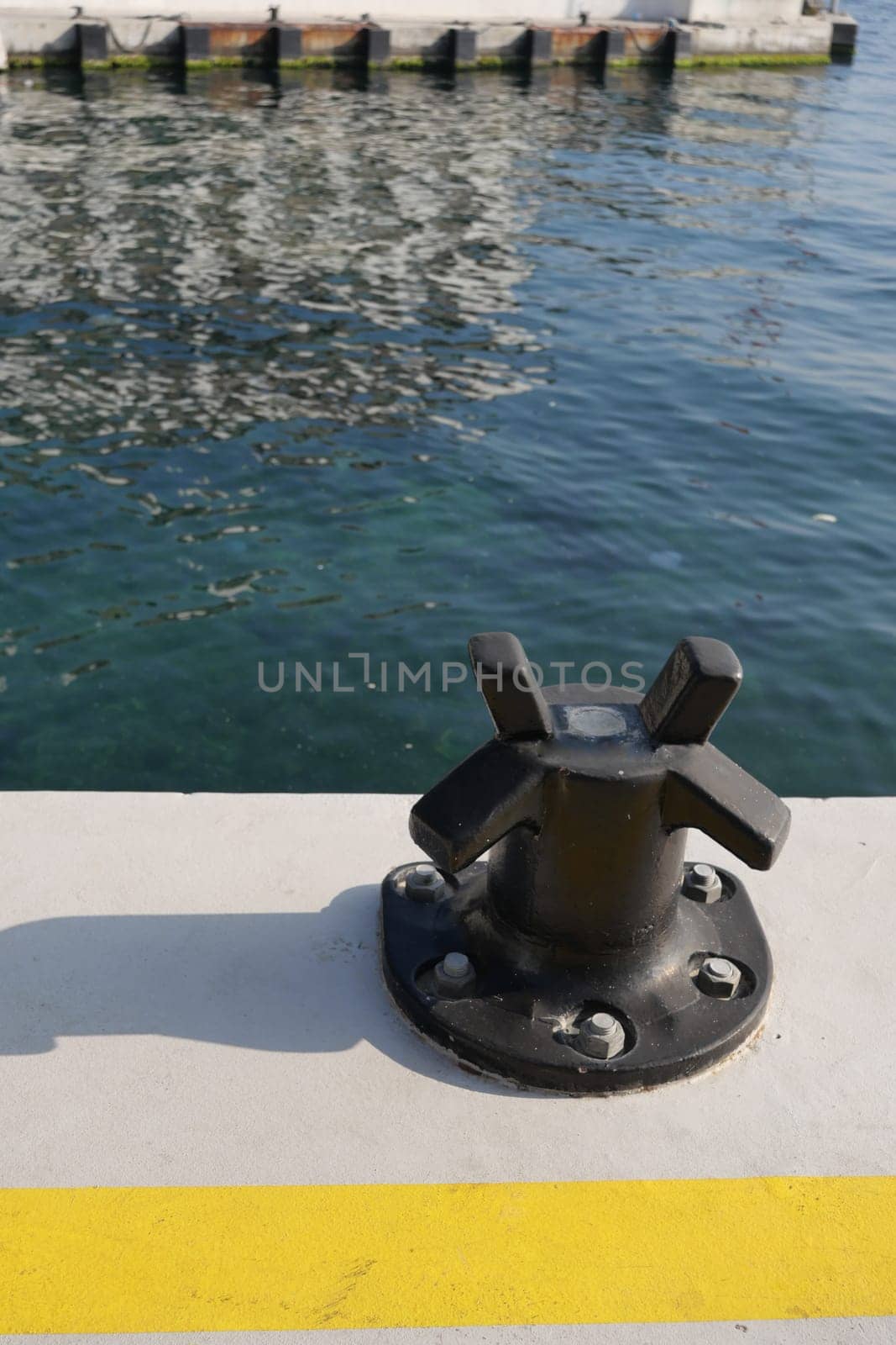 A black docking fixture stands on a pier with rippling water nearby.