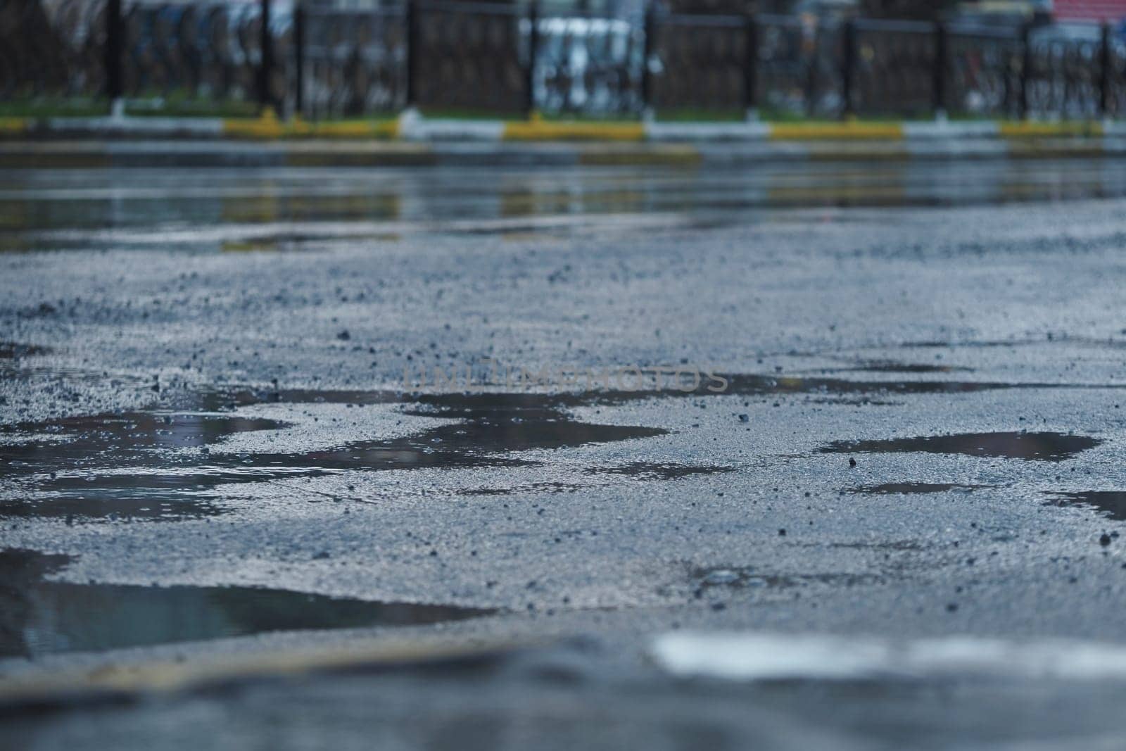 Puddles collect on a city street pavement after a rainy day.