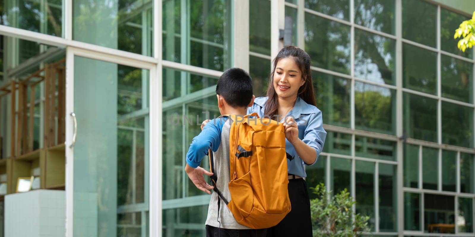 A mother assists her son with his backpack, ensuring he's ready for school. This scene embodies the nurturing aspect of parenting and childhood preparation.
