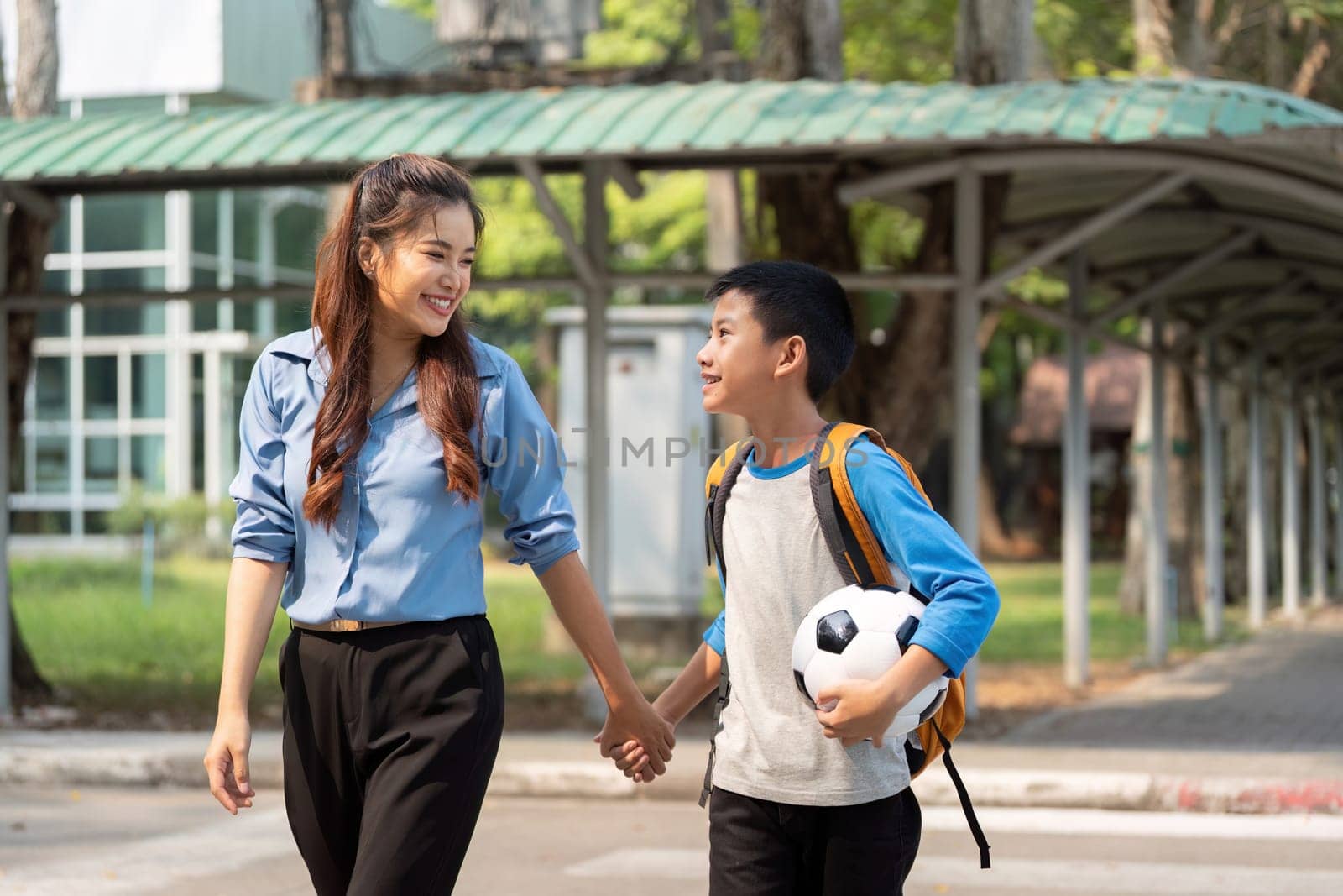 This touching scene captures a mother and son talking animatedly as they walk to school, with dreams of soccer in the air.