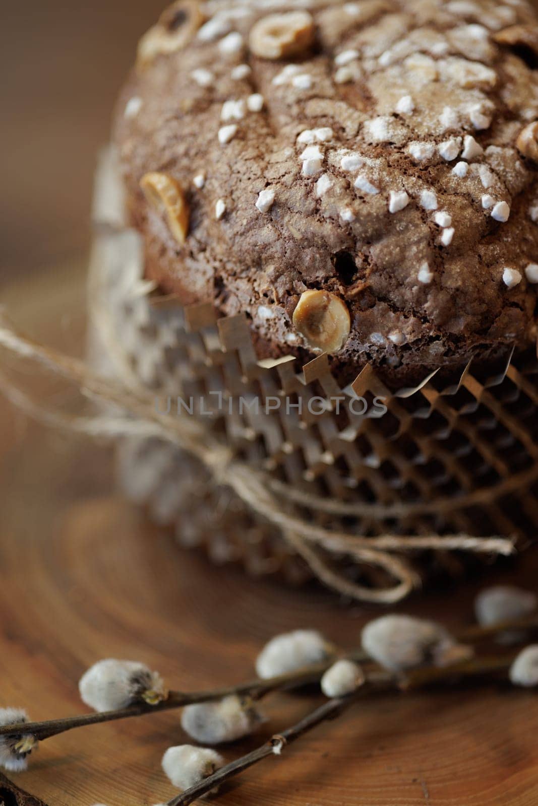 Close-up of traditional Easter sweet bread with hazelnuts and sugar on wooden background with pussy willow.