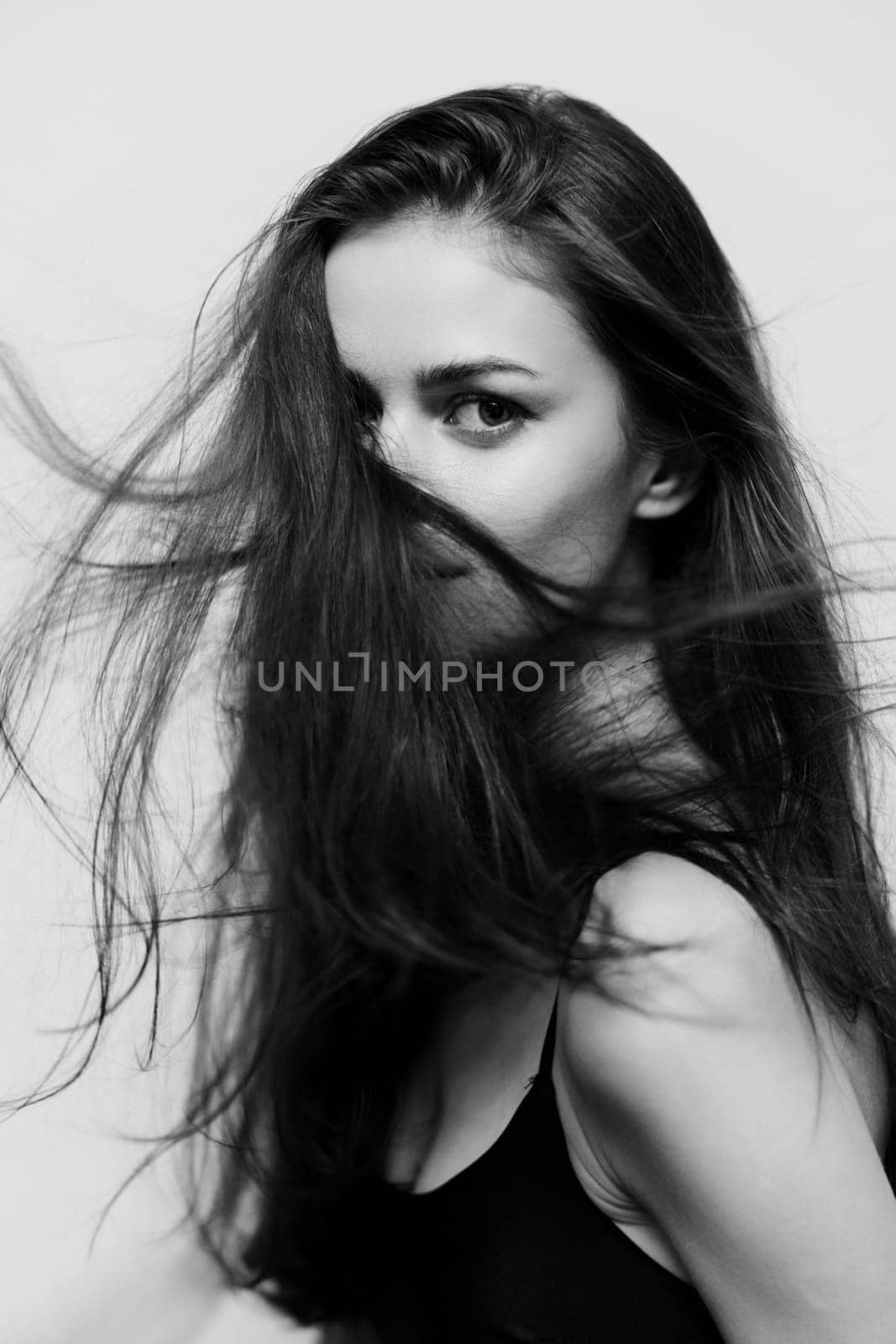 Striking portrait of a confident young woman with long hair in motion, showcasing beauty and elegance. Ideal for fashion and lifestyle imagery.
