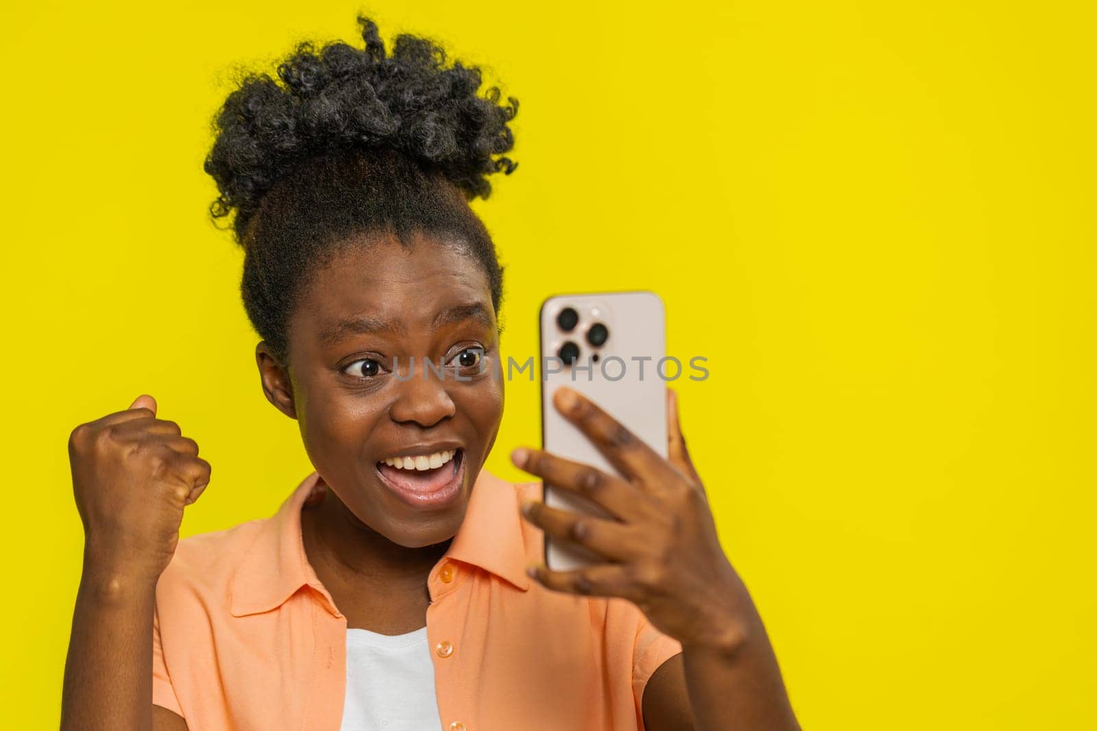 Happy excited African Black woman girl use smartphone typing browsing shouting say wow yes found out great big win good news lottery goal achievement celebrating success, winning play game on yellow