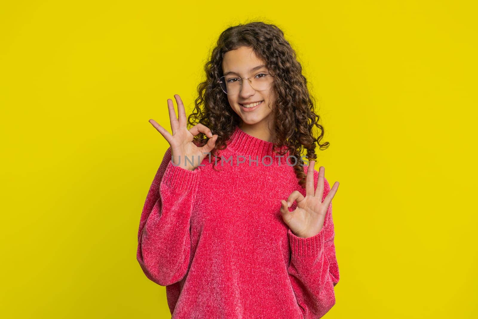Okay. Happy Caucasian young teenager girl looking approvingly at camera showing ok gesture, like sign positive feedback, approve something good, celebrate victory. Teen child kid on yellow background