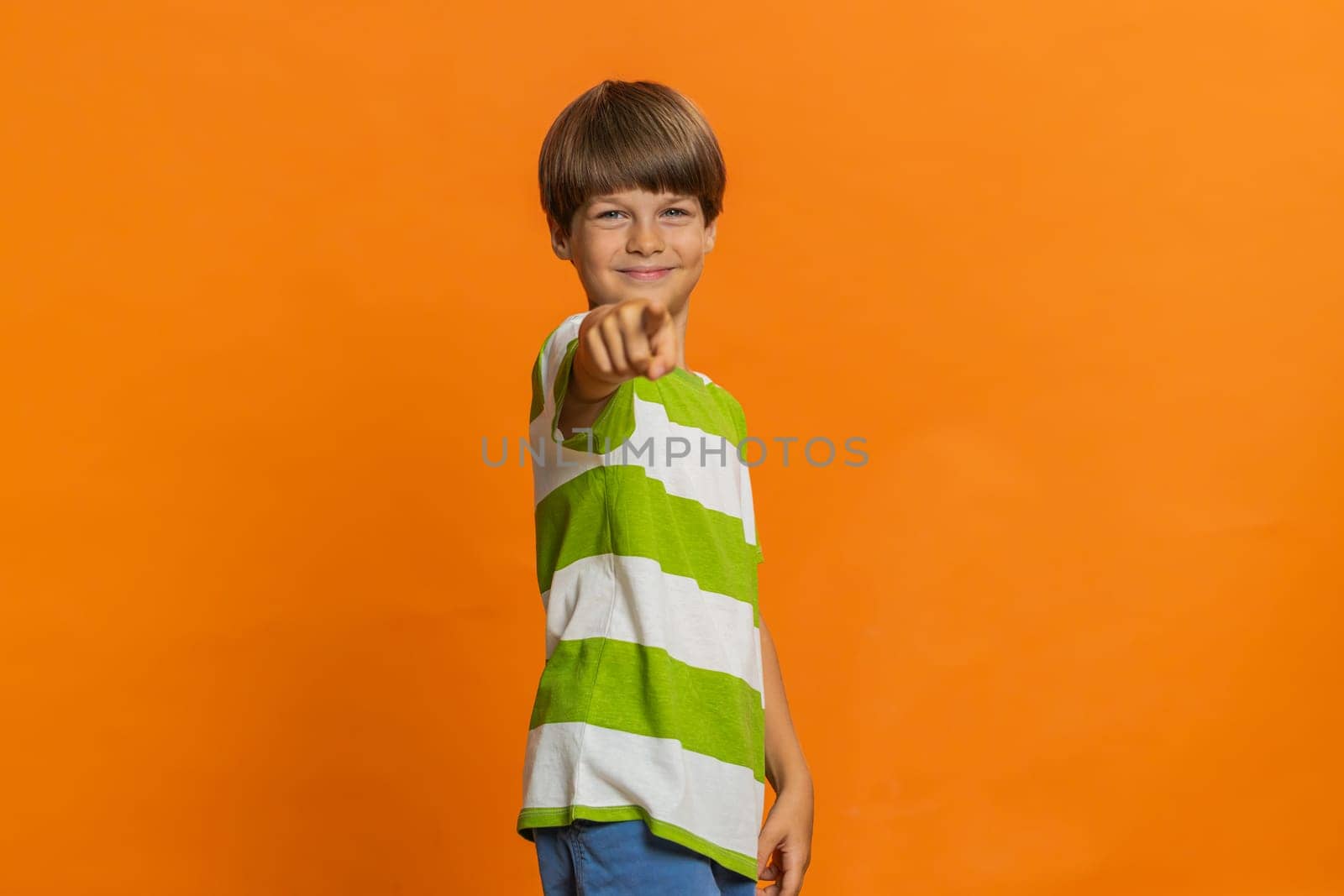 Happy preteen child boy kid laughing out loud after hearing ridiculous anecdote reaction on funny joke feeling carefree amused. Positive people. Little children isolated on studio orange background
