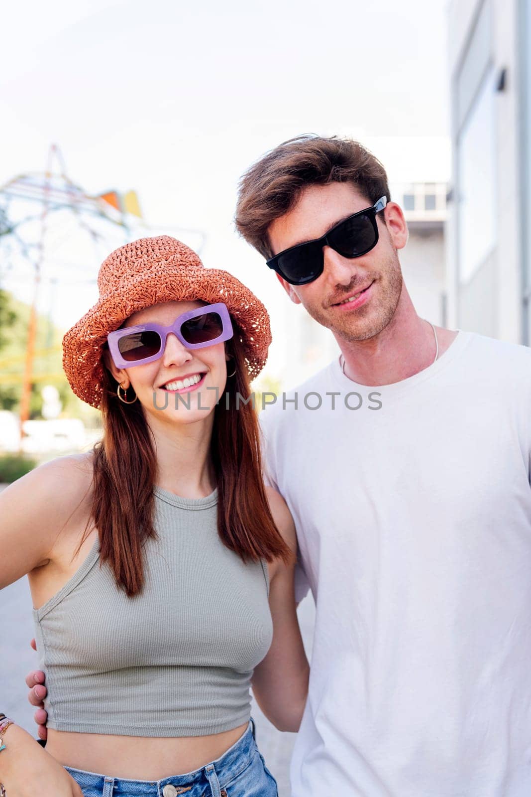 young couple smiling happy looking at camera, the woman is wearing a hat and sunglasses, concept of youth and romance, copyspace for text
