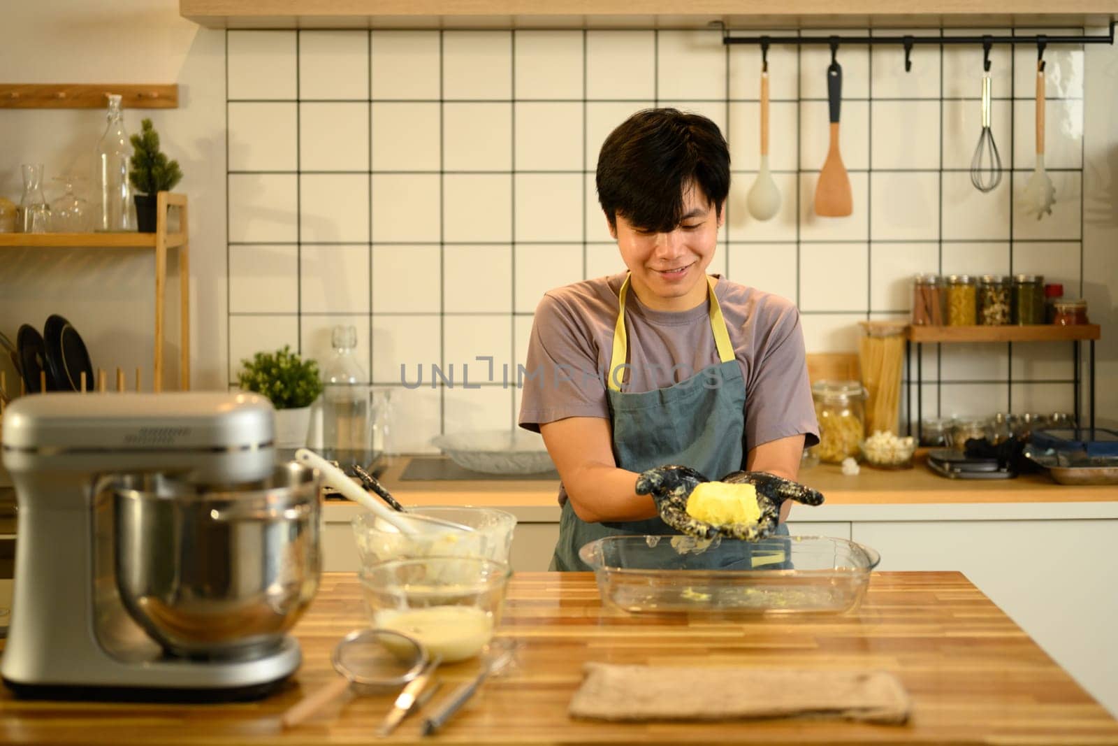 Young man shaping freshly made butter by hand in a kitchen.