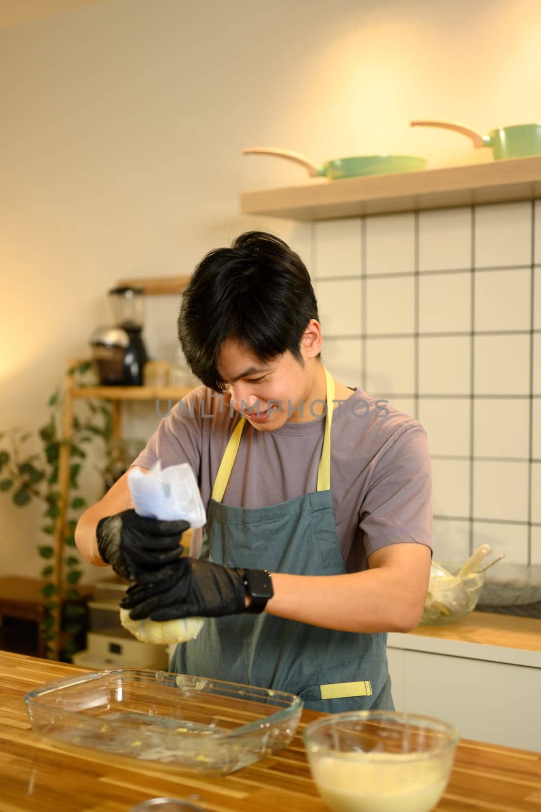 Young man squeezing fresh buttermilk from homemade butter in a kitchen.