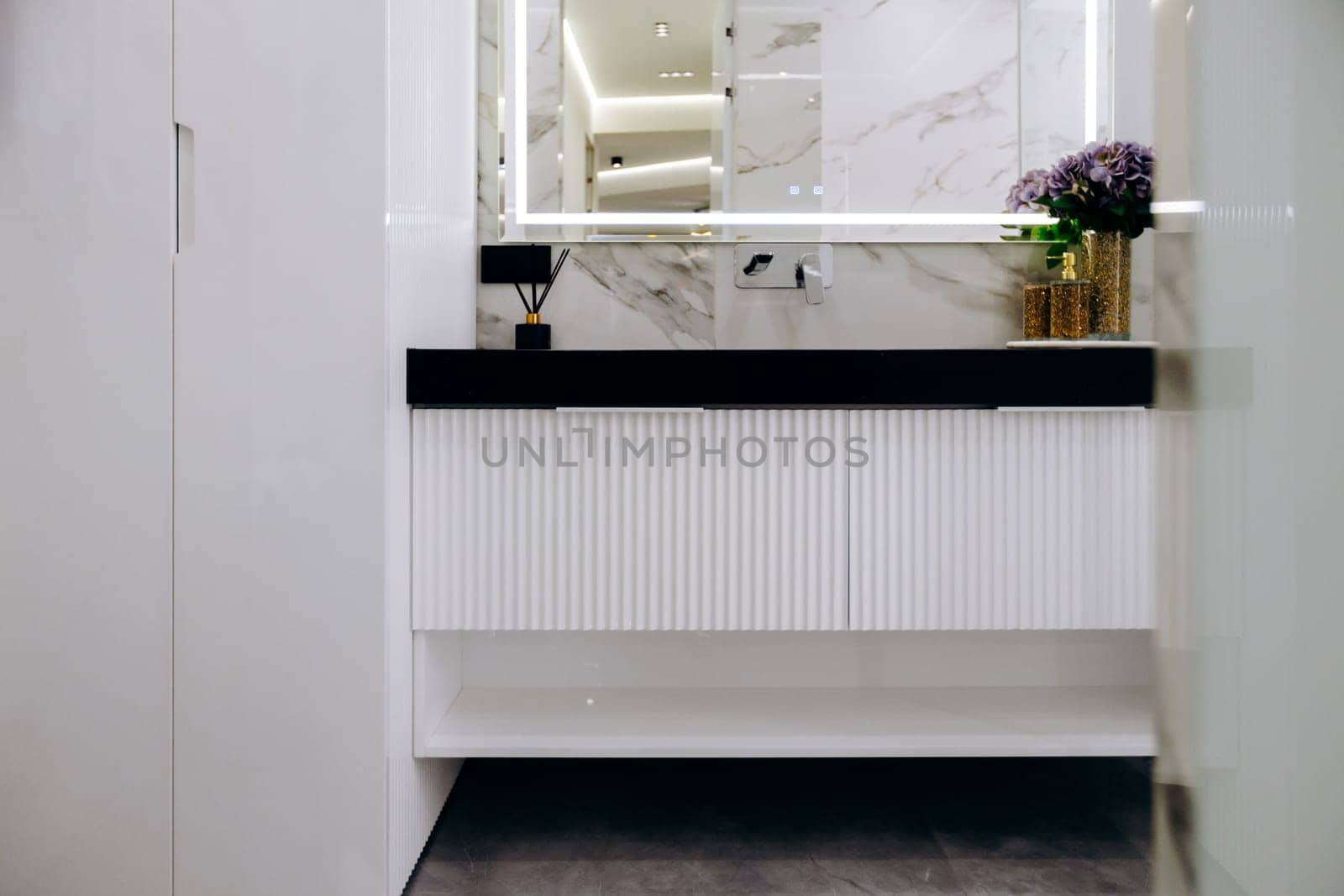 This is a beautifully designed bathroom that features a stylish sink, an elegant mirror, and vibrant flowers adorning the countertop