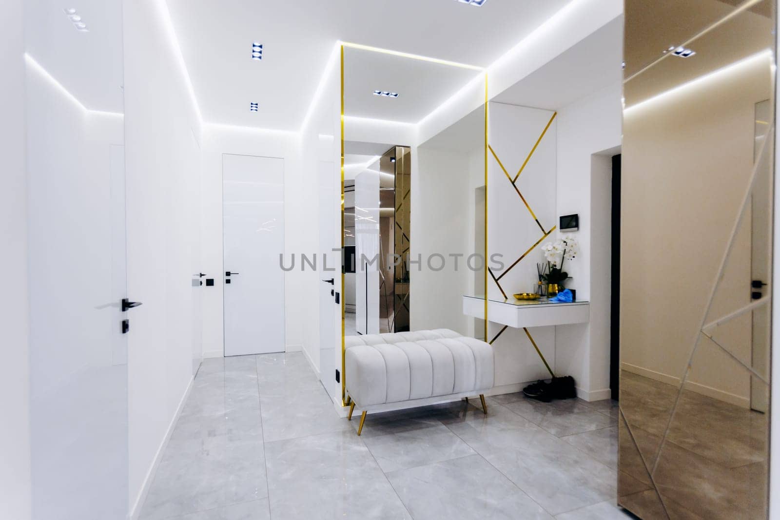 In a hallway, there is a wooden bench and a large mirror mounted on the wall, which enhances the aesthetic appeal of the space