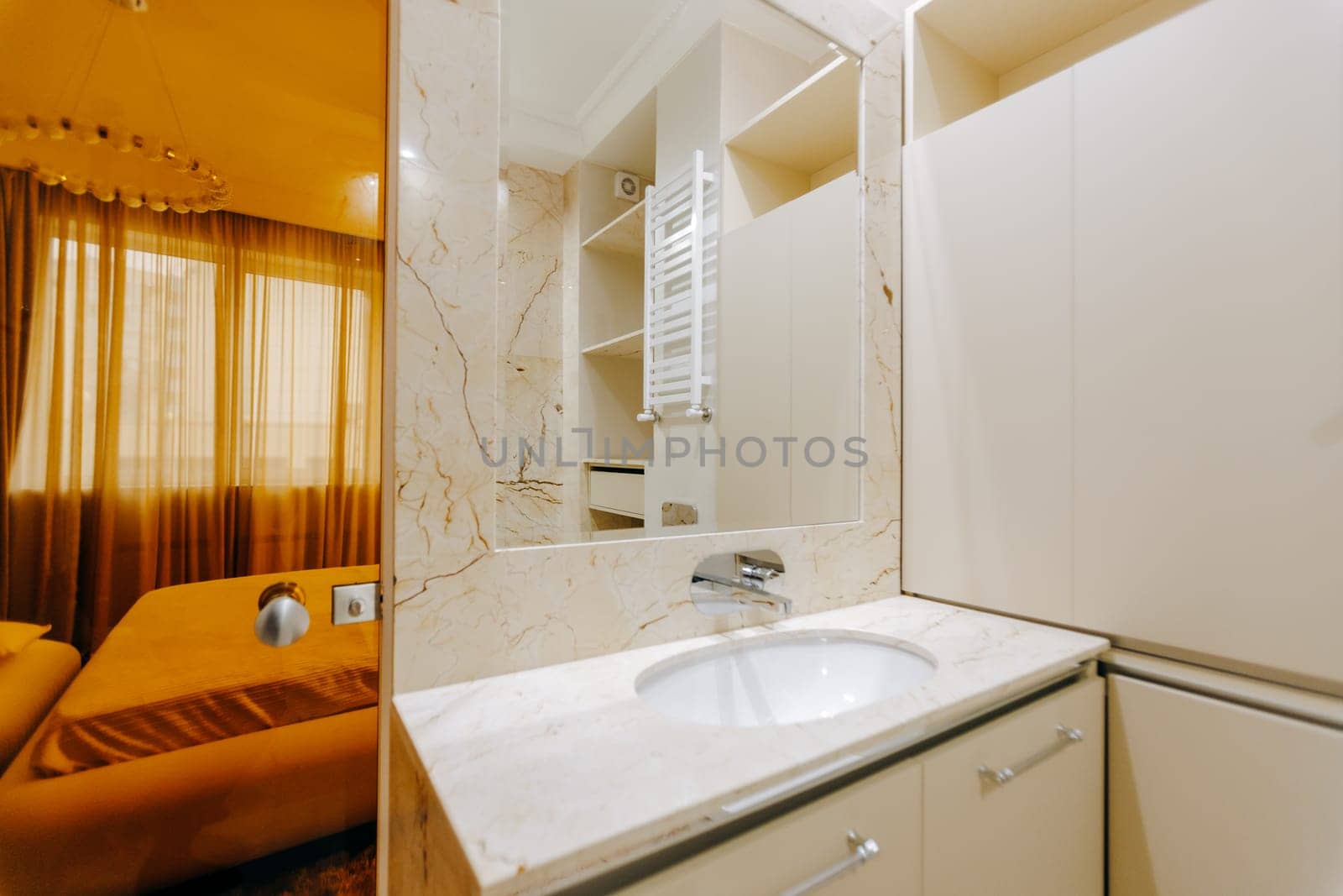 A welldesigned bathroom that includes a sink feature and a spacious, elegantly styled large mirror, enhancing the overall aesthetic appeal