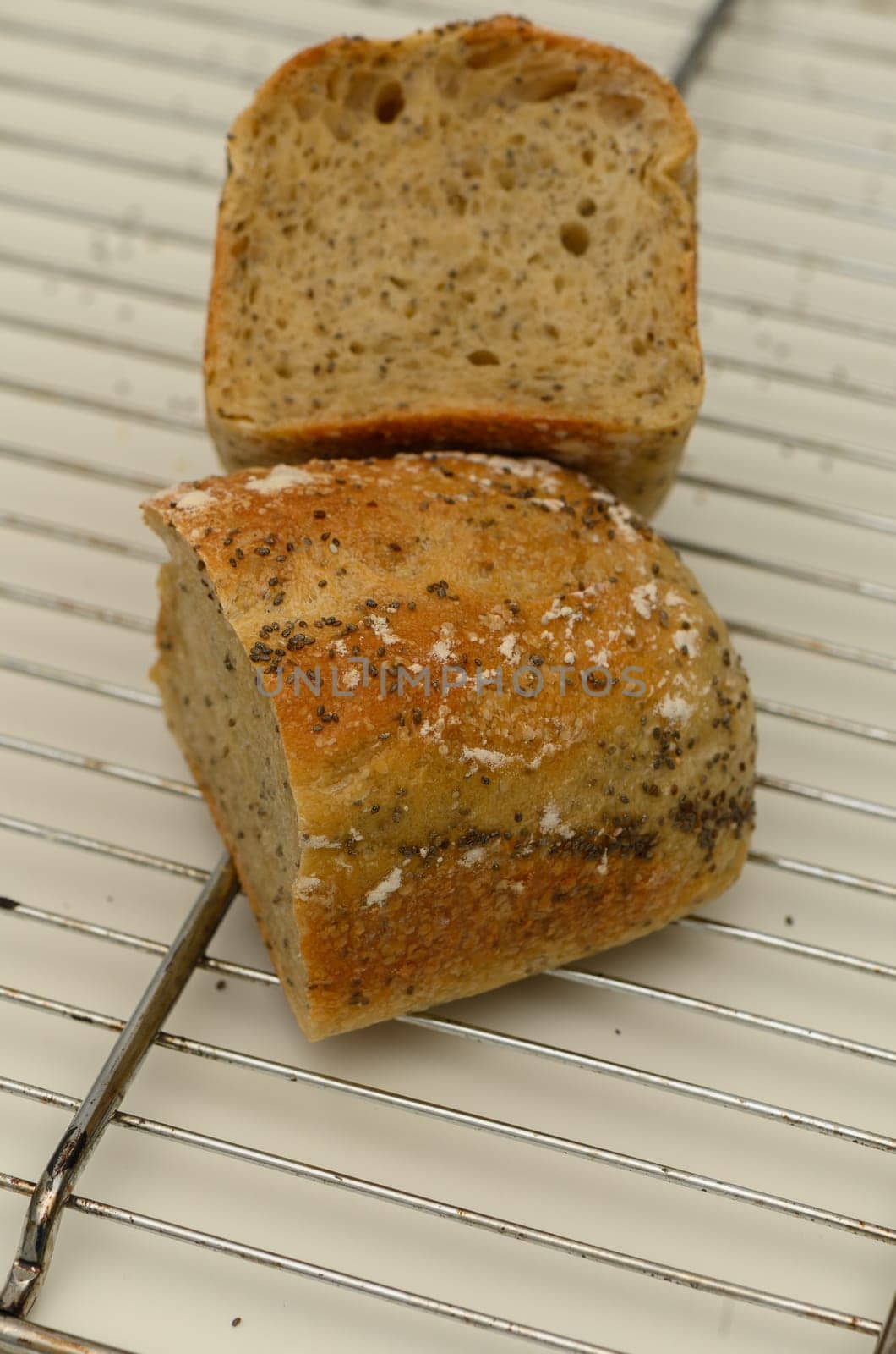 Freshly baked artisan bread, golden brown and crusty on the outside, cools on a wire rack. The loaf is partially sliced, revealing a soft, airy texture inside, inviting taste.