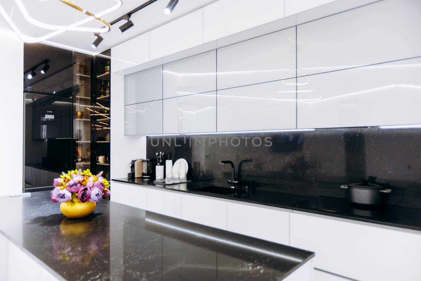 This is a beautiful kitchen featuring elegant white cabinets paired with sleek black countertops, and a vibrant bowl of colorful flowers placed on the counter, adding a touch of cheerfulness