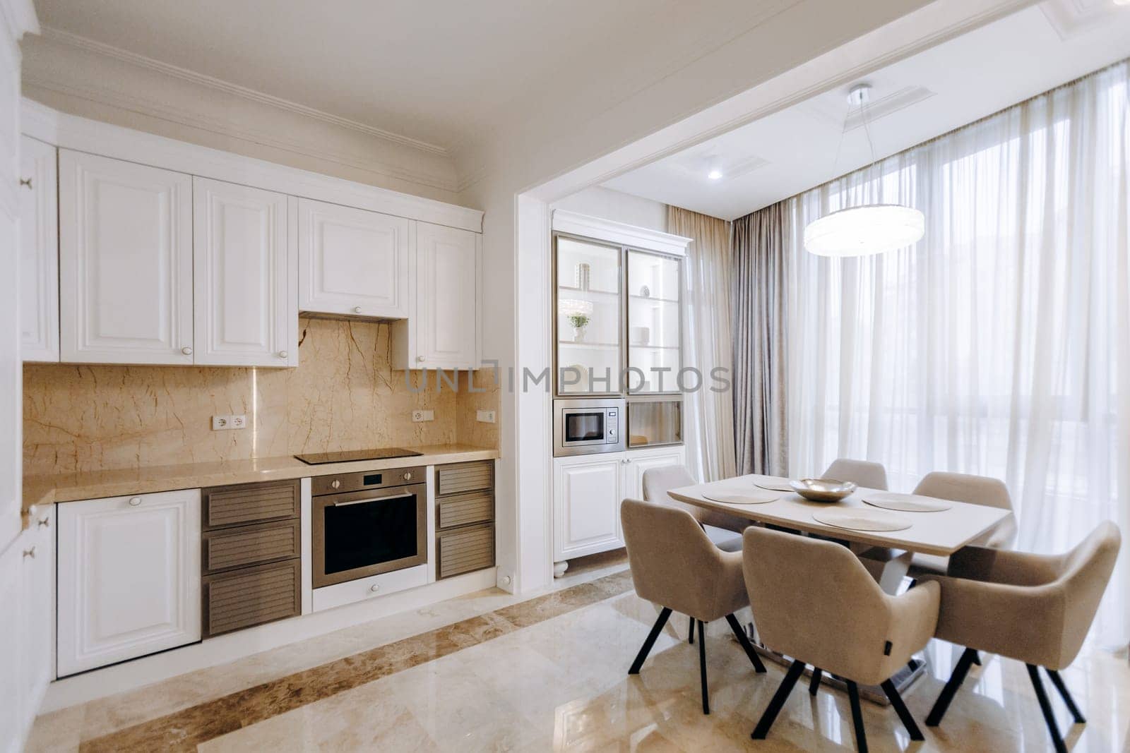 In a lovely house, there exists a kitchen and a dining room that features a wellset table accompanied by several comfortable chairs