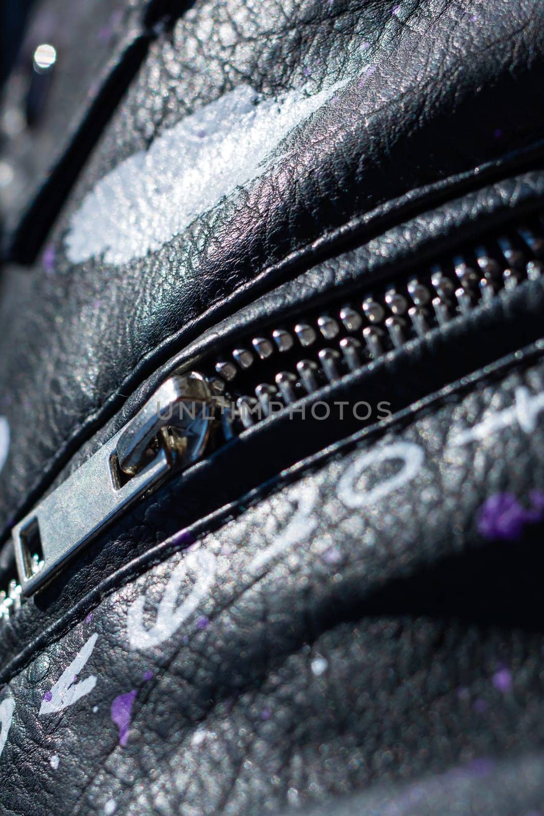 This image captures a detailed close up of a zipper that is prominently featured on a stylish black leather jacket