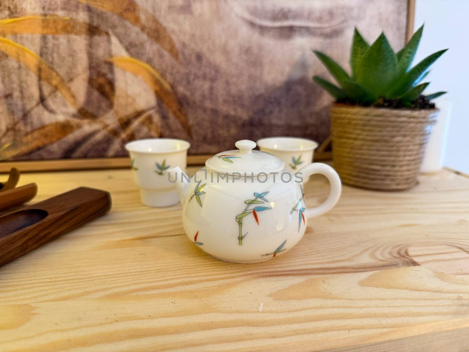 Small porcelain teapot with bamboo motif on wooden table. Harmony, tea culture, and peaceful atmosphere of traditional tea ceremony.