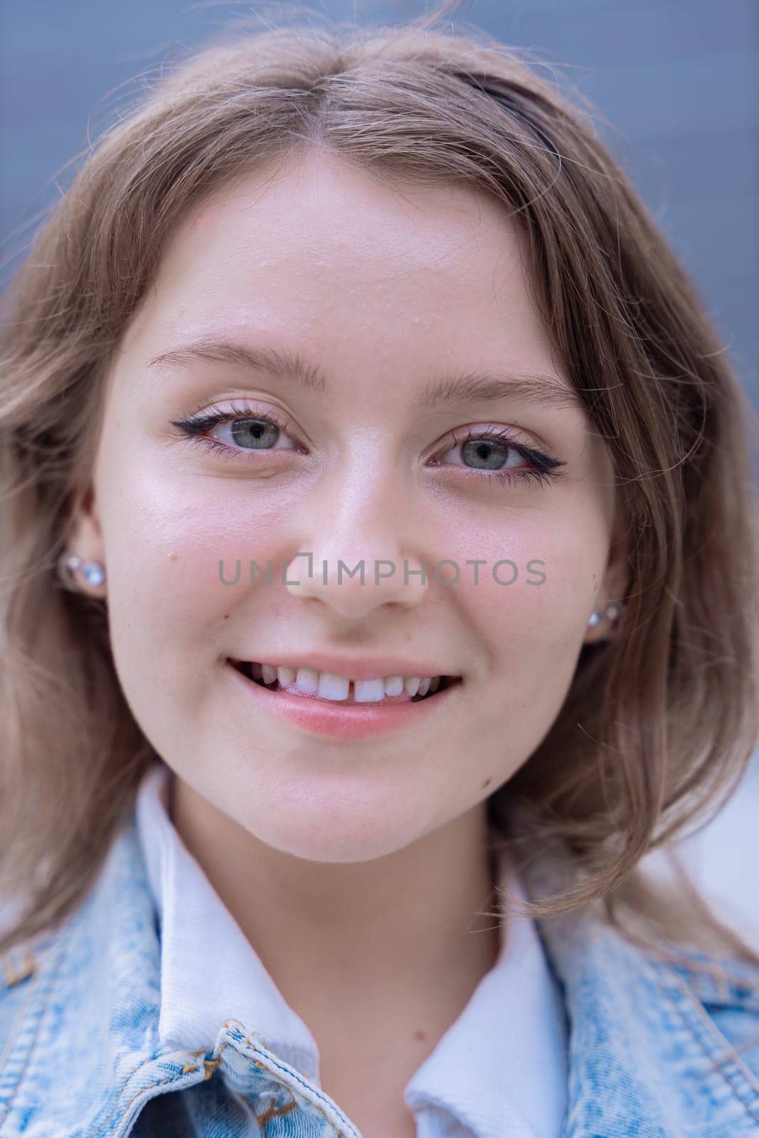 Vertical portrait Caucasian woman with a serious expression looking directly at the camera. The blurred urban background highlights her confident presence and emotional strength in the city.