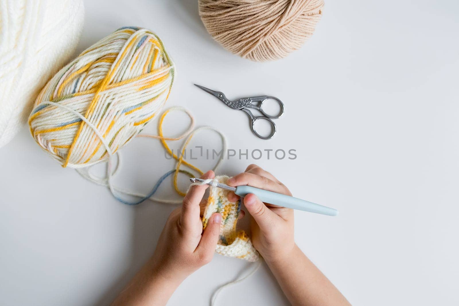 Child crocheting with yarn and crochet hook.