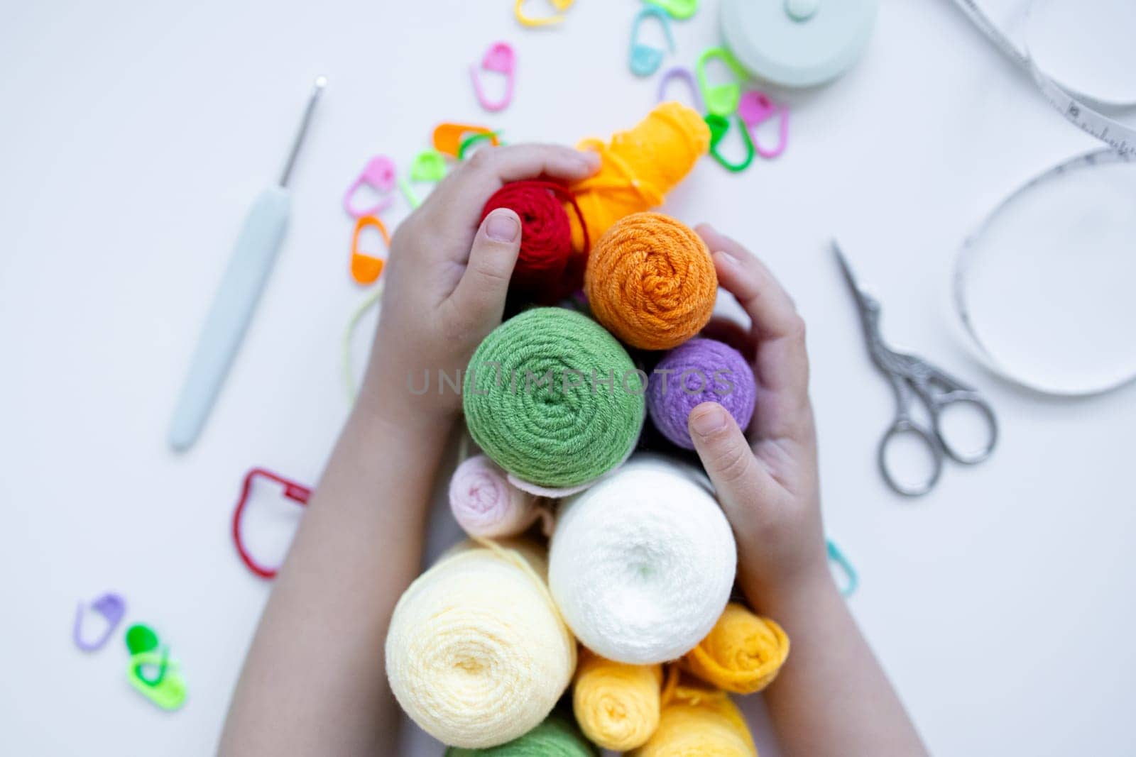 Child hands holding colorful yarn in creative craft scene.