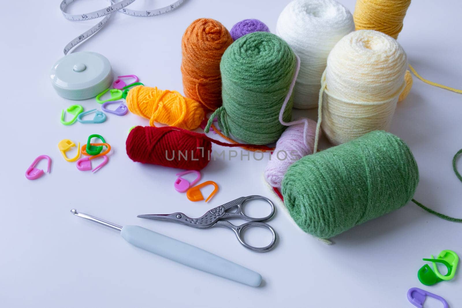 Colorful yarn and crochet accessories on white surface.