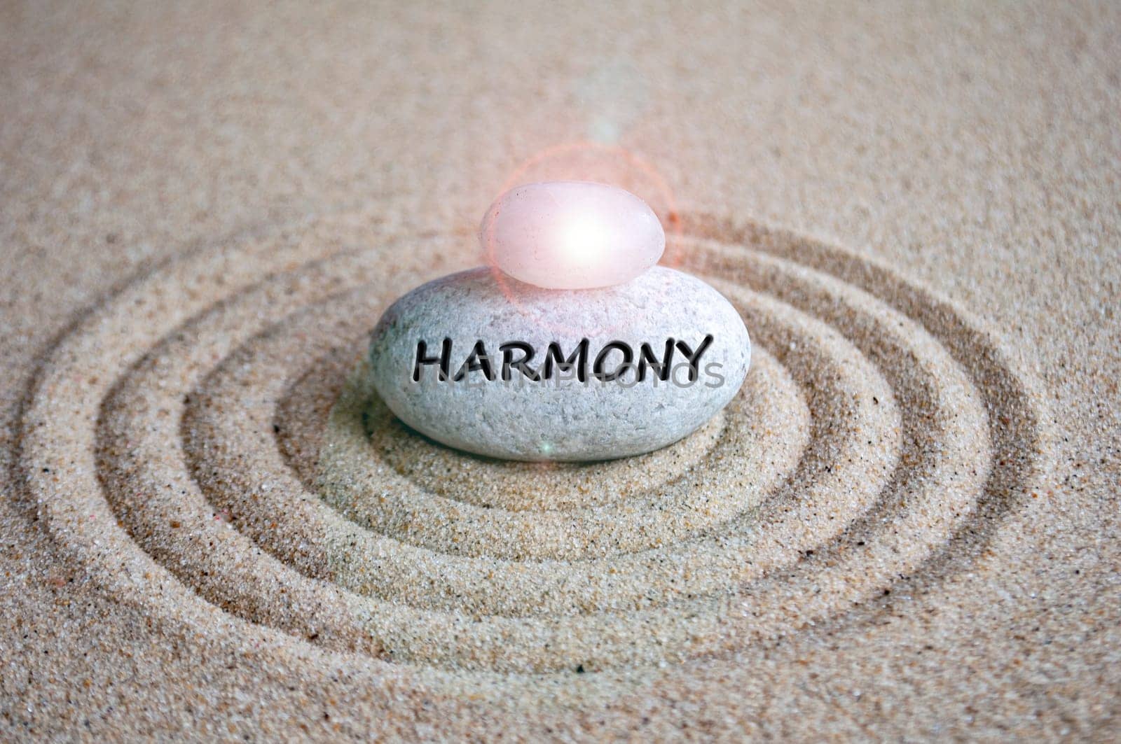 Harmony text engraved on zen stock with shining stone on top of sands.