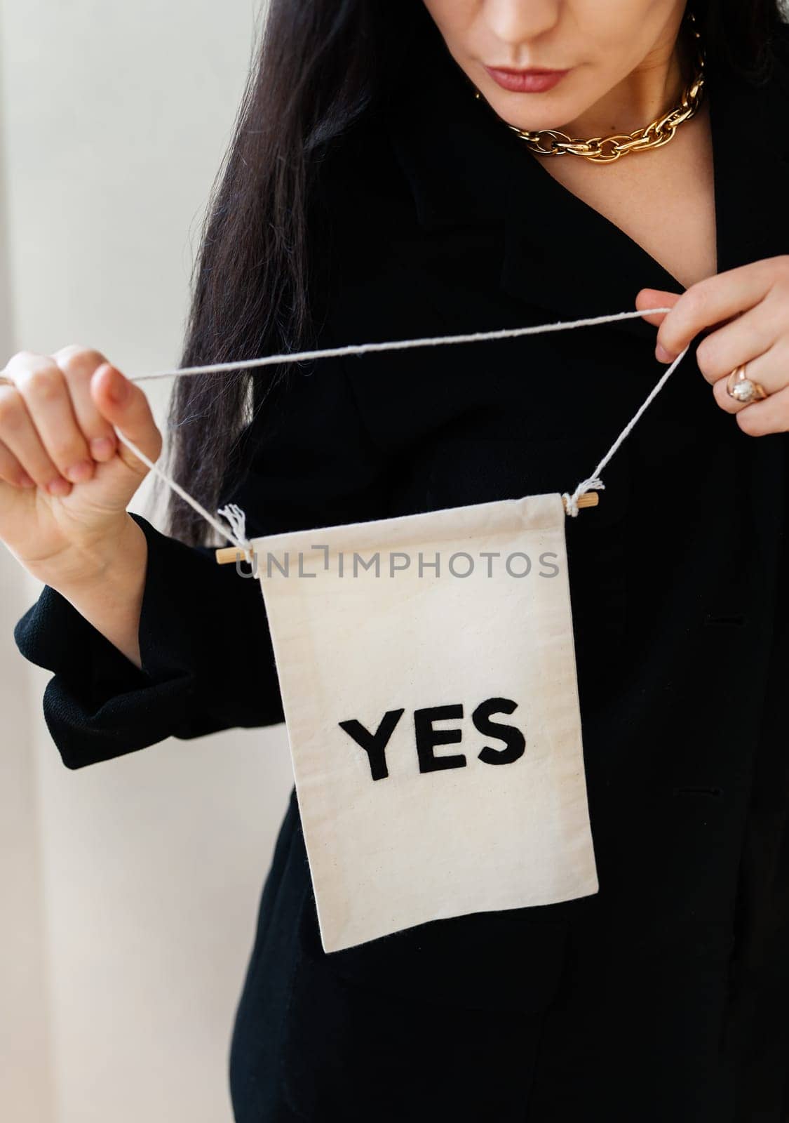 A woman in a black blouse holds a small banner that says 'YES', signifying agreement or affirmation.