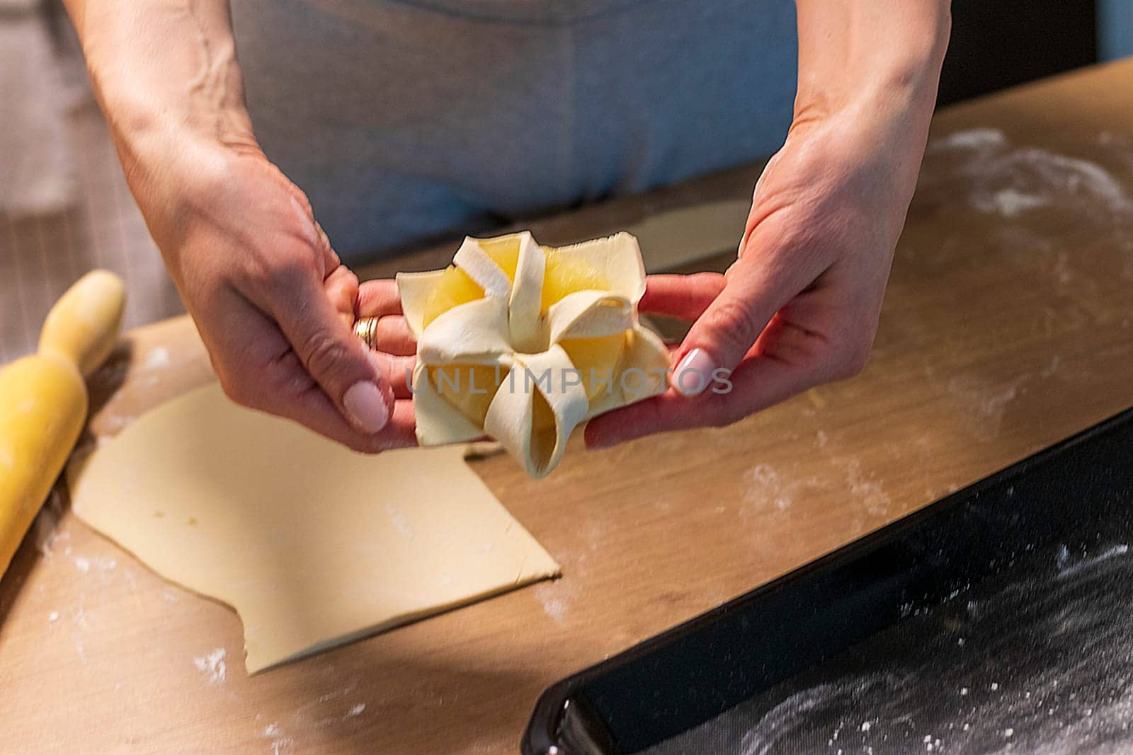 A woman wraps a pineapple wedge in puff pastry