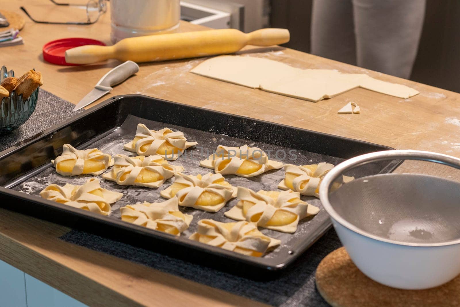 Shot of the a pineapple wedges wrapped in puff pastry on the baking tray on the kitchen counter