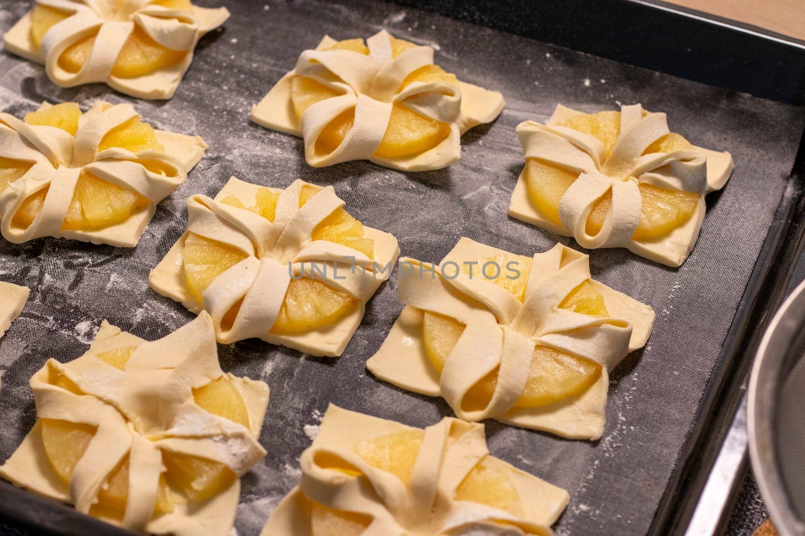 Shot of the a pineapple wedges wrapped in puff pastry on the baking tray