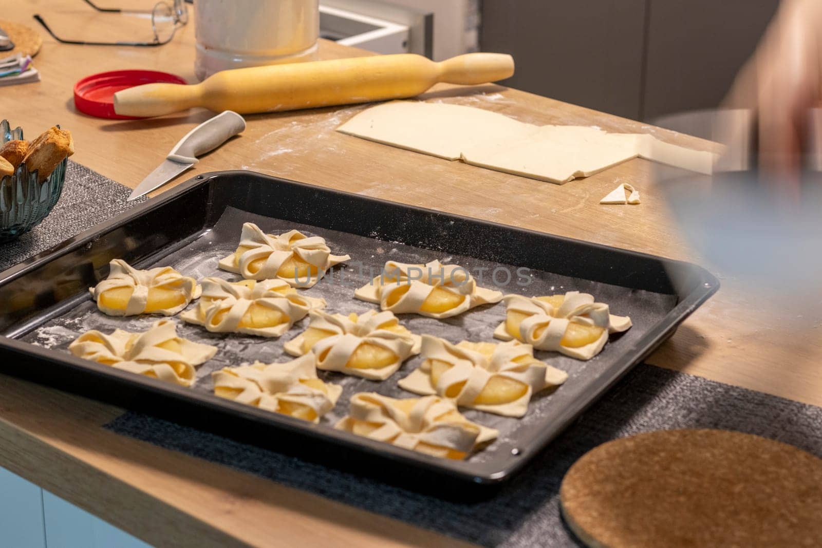 Shot of the a pineapple wedges wrapped in puff pastry on the baking tray on the kitchen counter