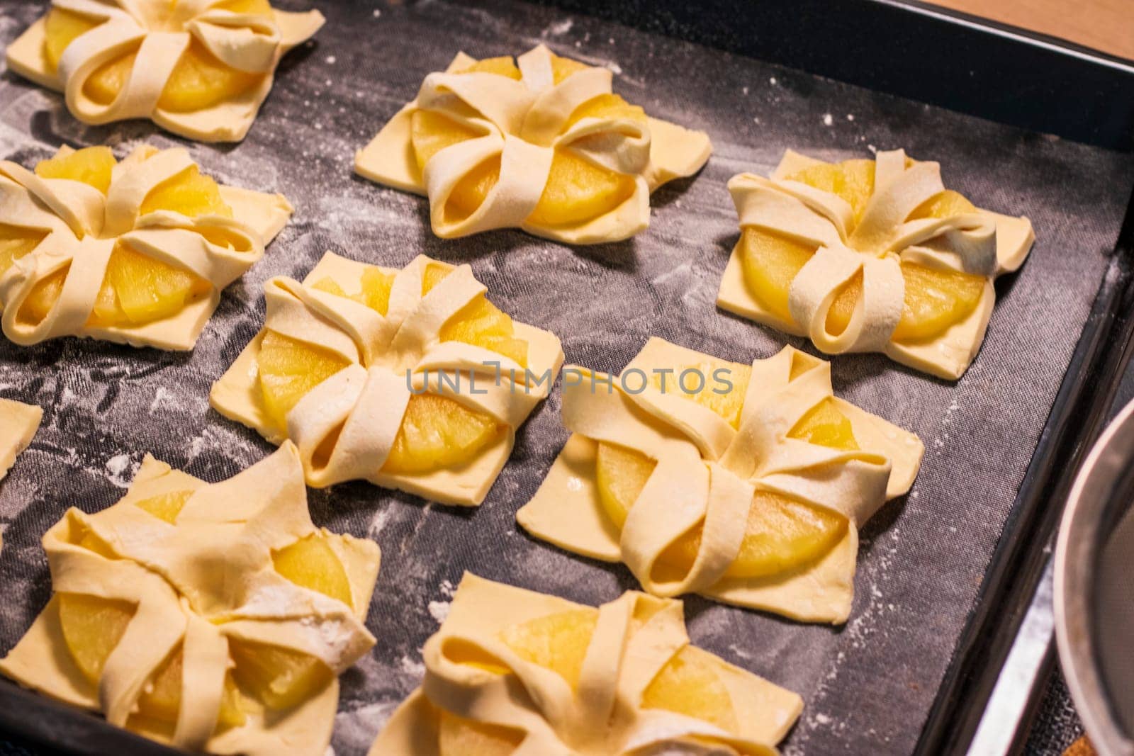 Shot of the a pineapple wedges wrapped in puff pastry on the baking tray