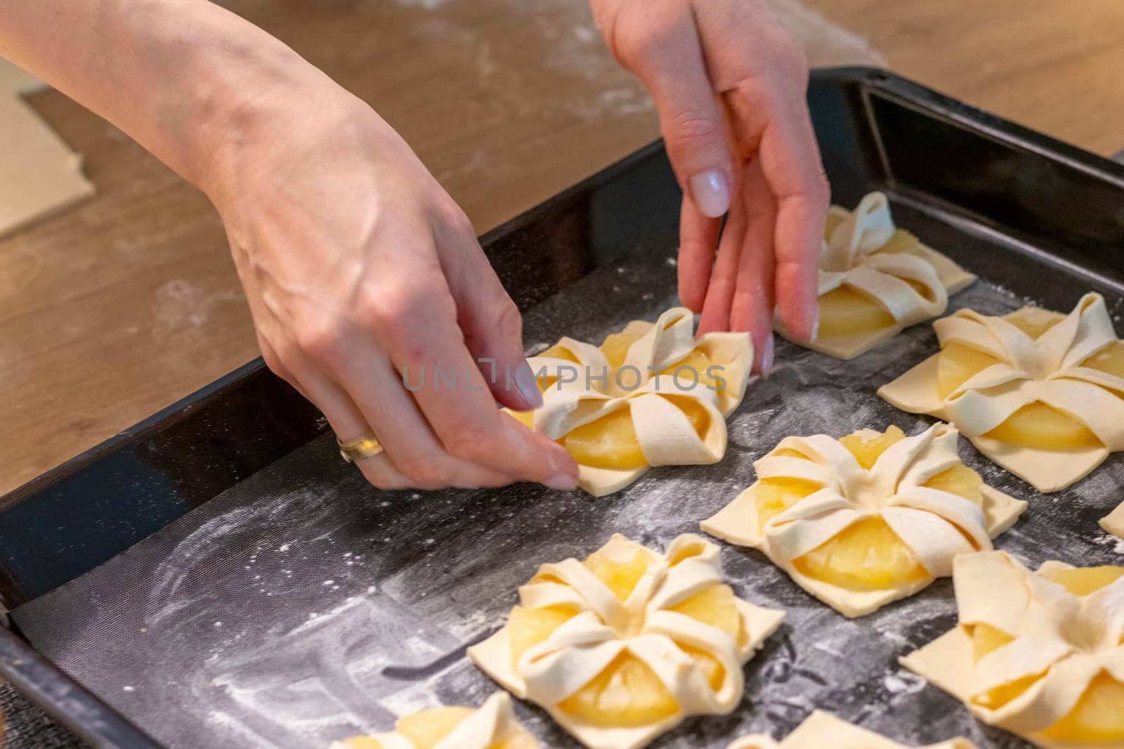 A woman places fruit puff pastry into the baking tray