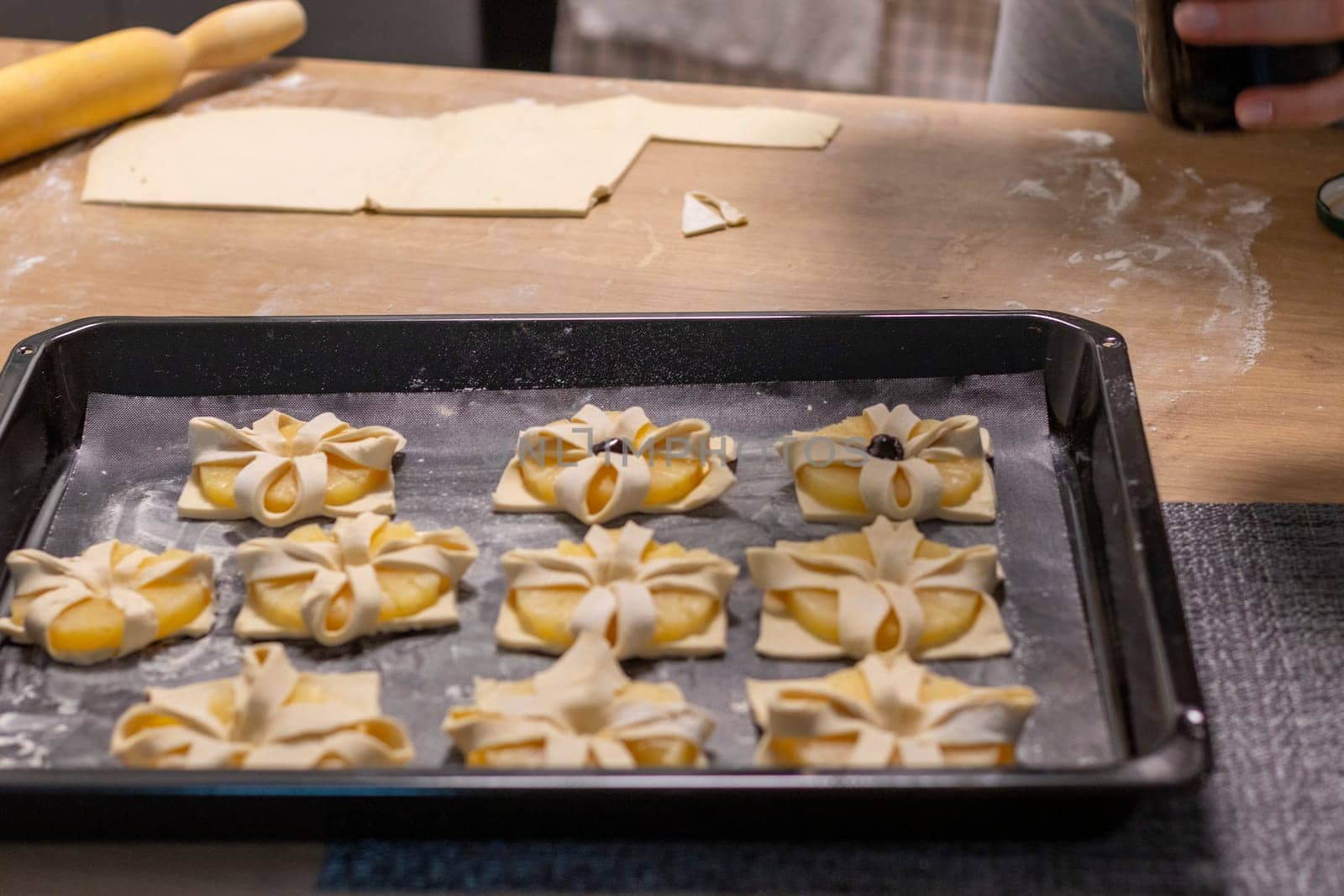 A woman place cherry on the top of the puff pastry with pineapple wedges wrapped.