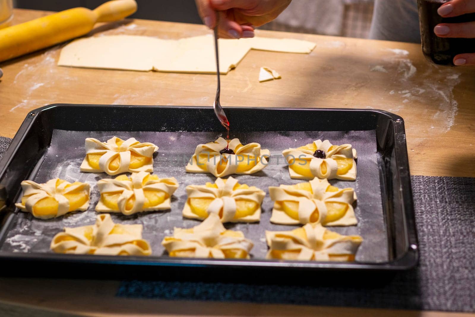A woman place cherry on the top of the puff pastry with pineapple wedges wrapped.