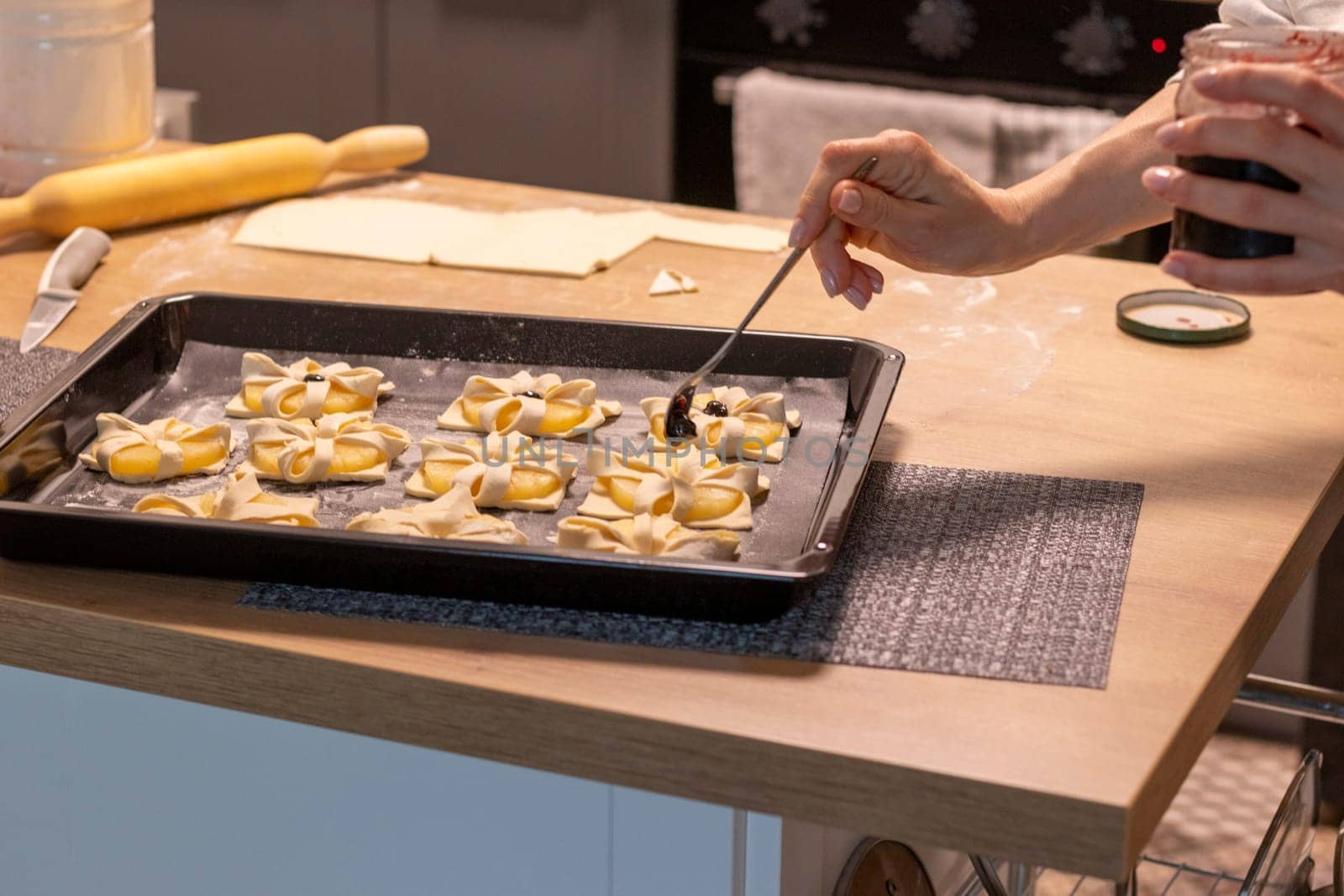A woman place cherry on the top of the puff pastry with pineapple wedges wrapped.