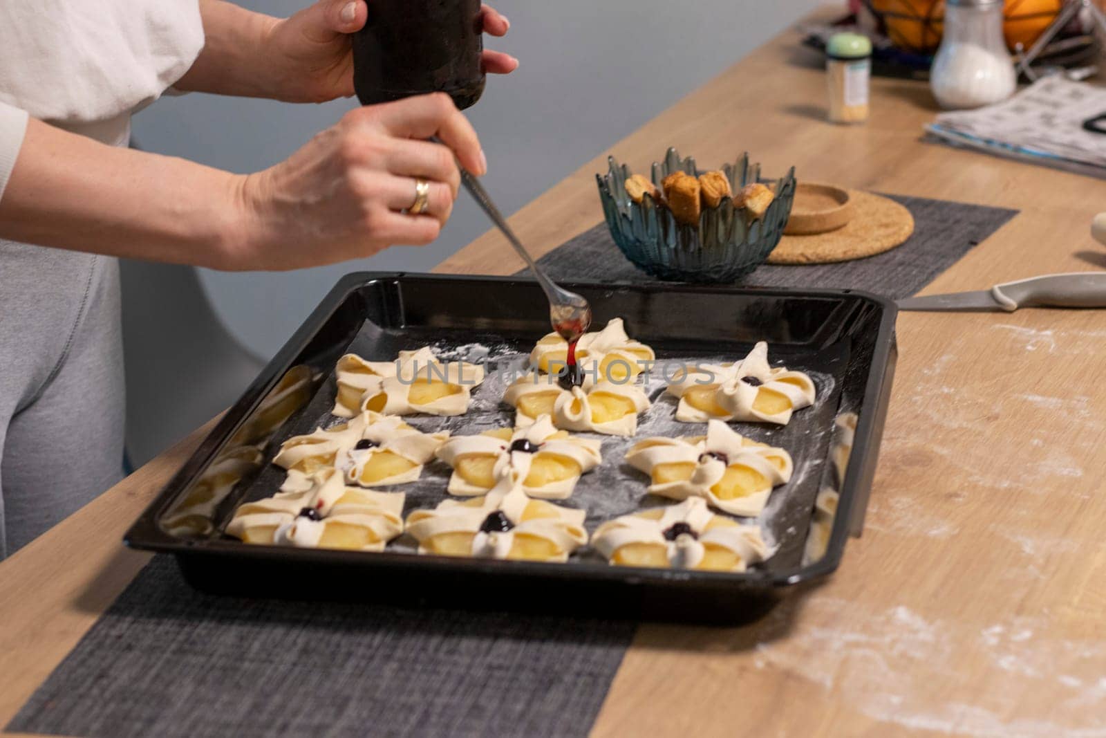 A woman place cherry on the top of the puff pastry with pineapple wedges wrapped.