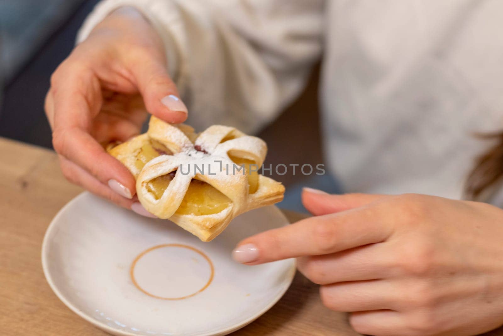 A woman picks freshly baked fruit puff pastry on the ceramic plate