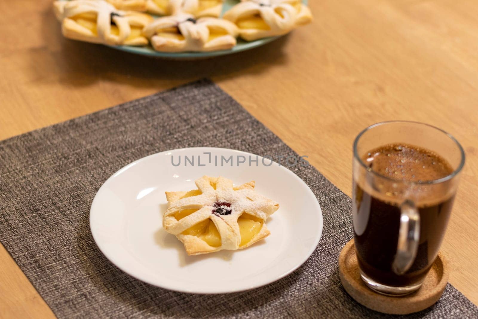 Freshly baked fruit puff pastry on the ceramic plate next to hot cup of coffee