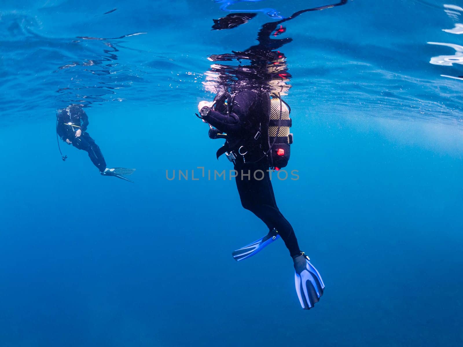 underwater view of unrecognizable scuba diver waiting on the surface of the ocean, concept of active lifestyle and sea adventure, copyspace for text