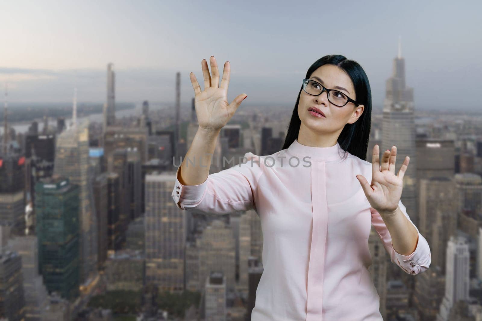Young asian woman interacts with invisible virtual screen by her hands.