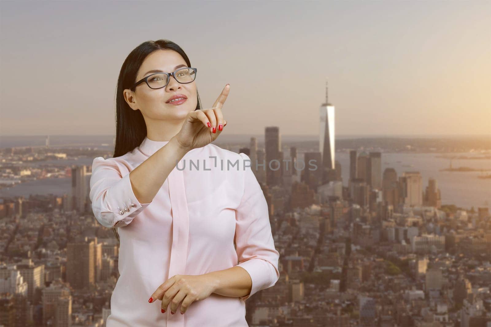 Asian businesswoman is using an invisible virtual screen. Urban evening cityscape background.