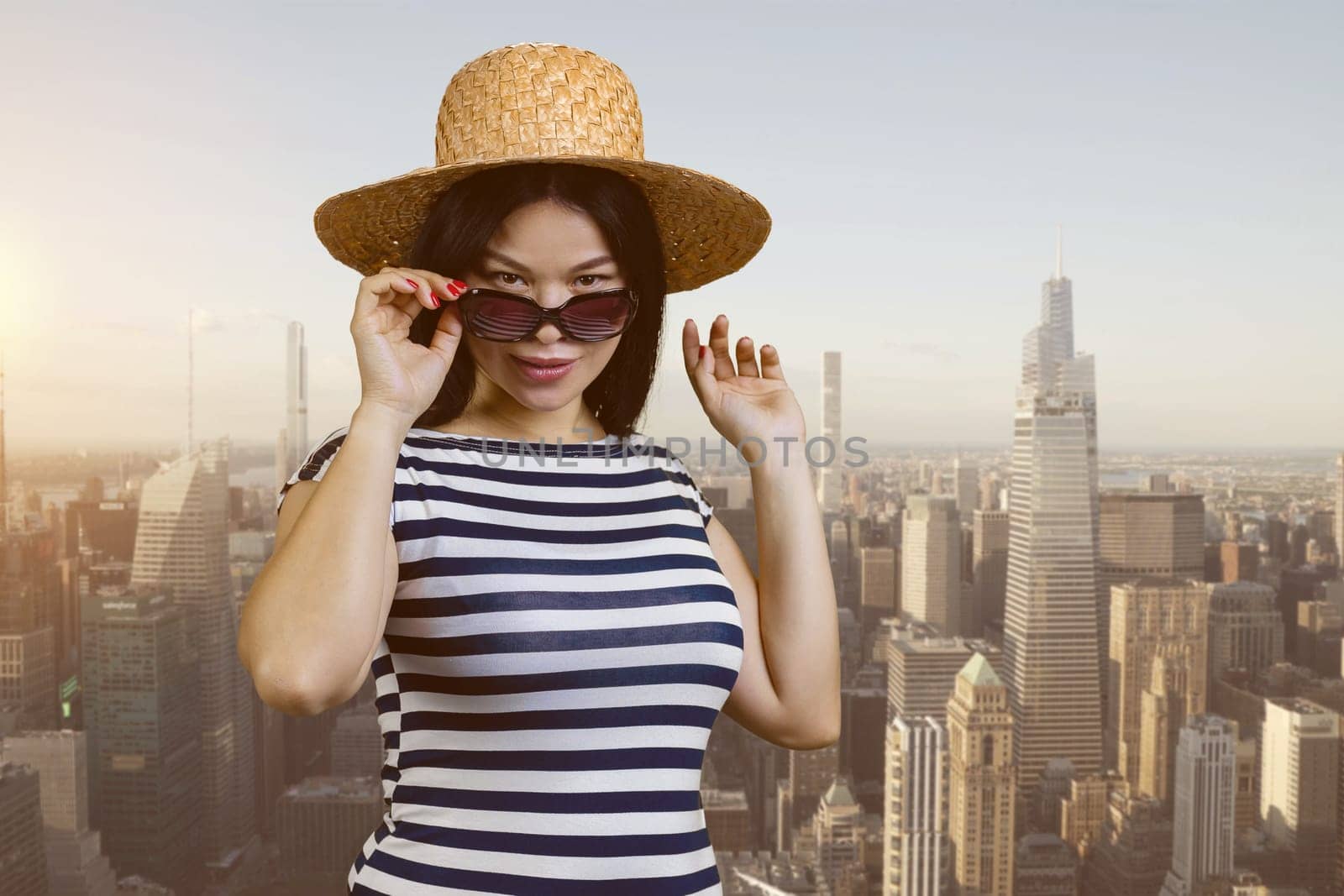 Portrait of a young sexy asian woman in straw hat and sunglasses. Urban cityscape background.