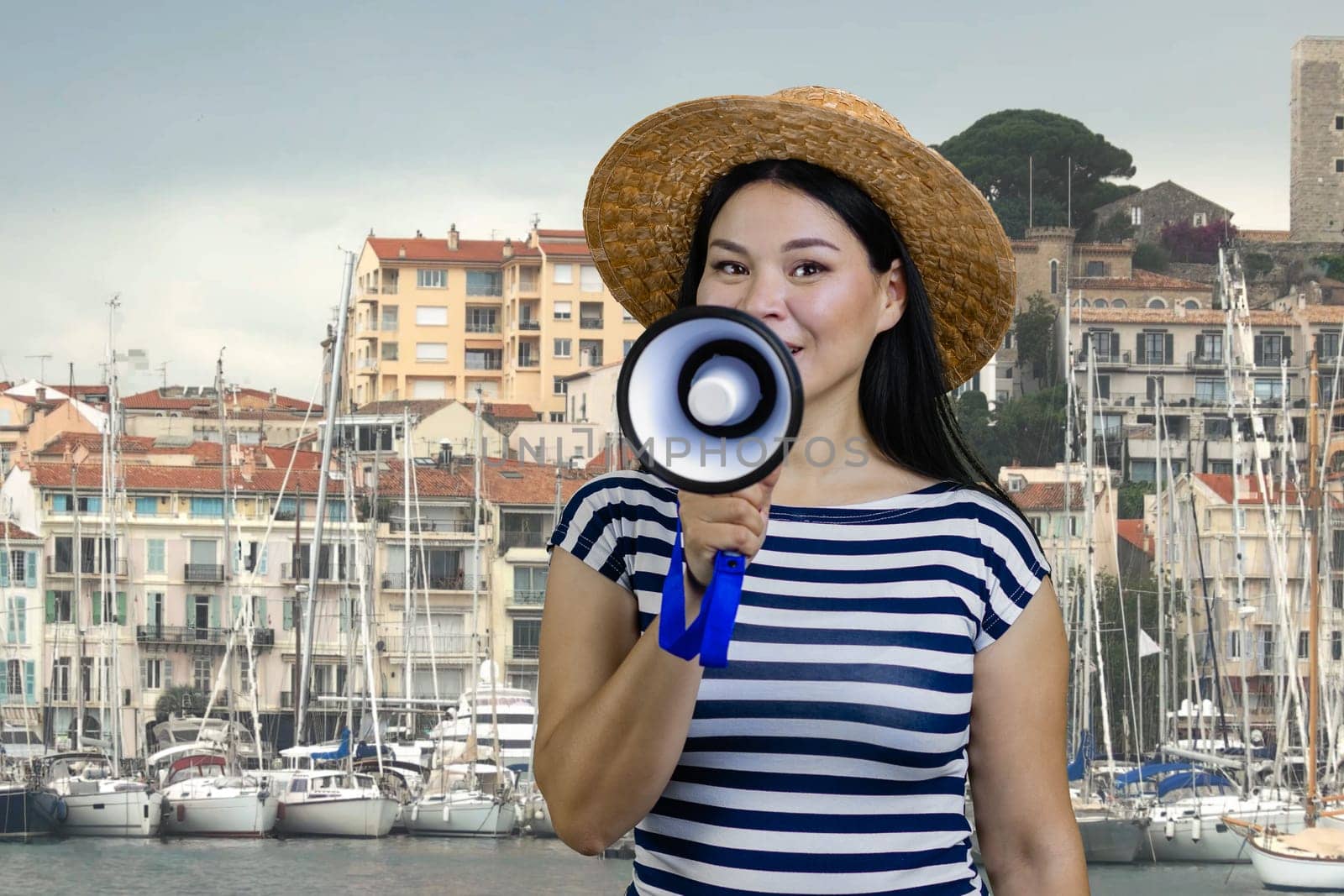 Young asian woman with megaphone against yacht harbour background. Female tourist guide with loudspeker.