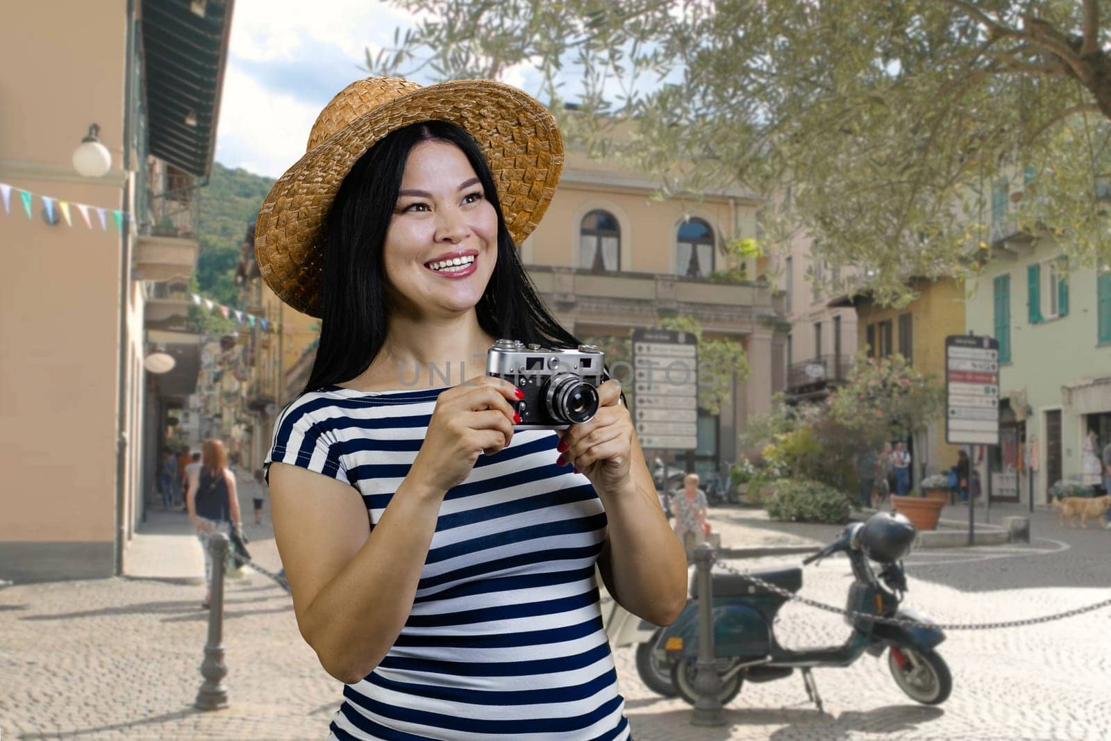 Young cheerful asian womanwith vintage photo camera standing on the street. Female tourist making a photos of sighteeing.