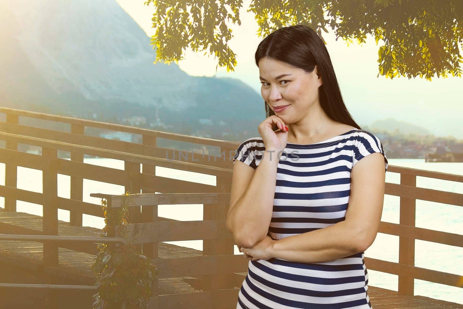 Portrait of attractive brunette asian woman on vacation. Glance at you. Summer resort background.