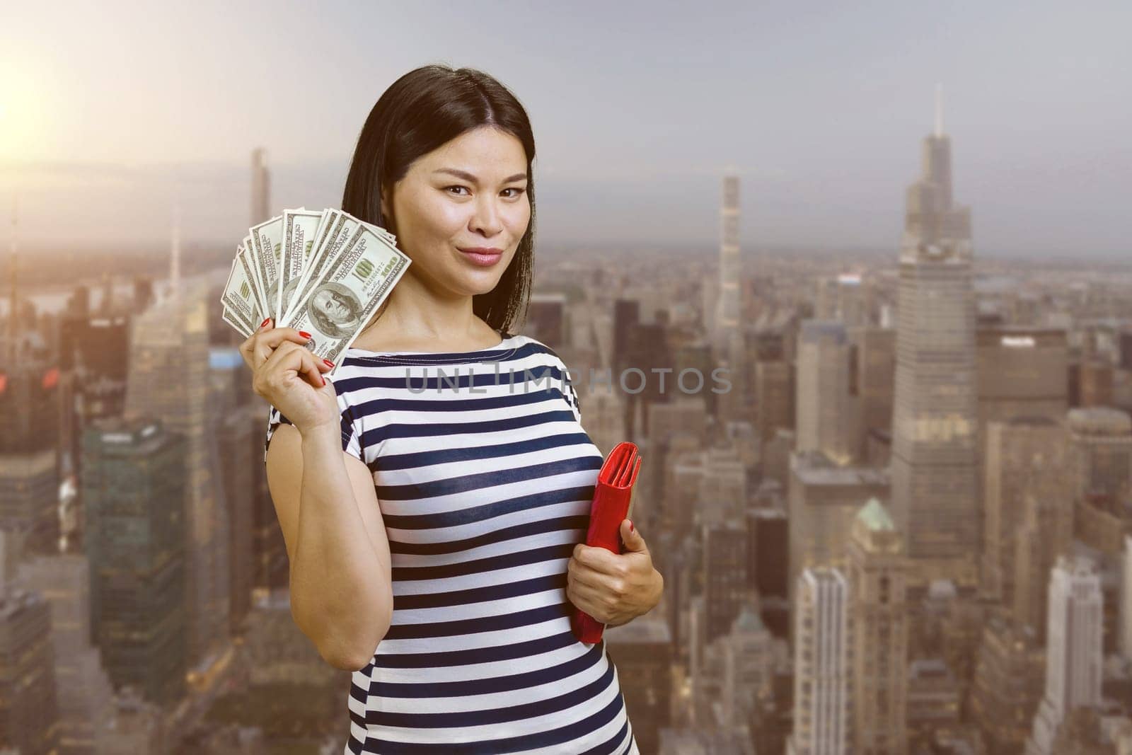 Young korean woman with fan of money from a red wallet. Urban cityscape background.