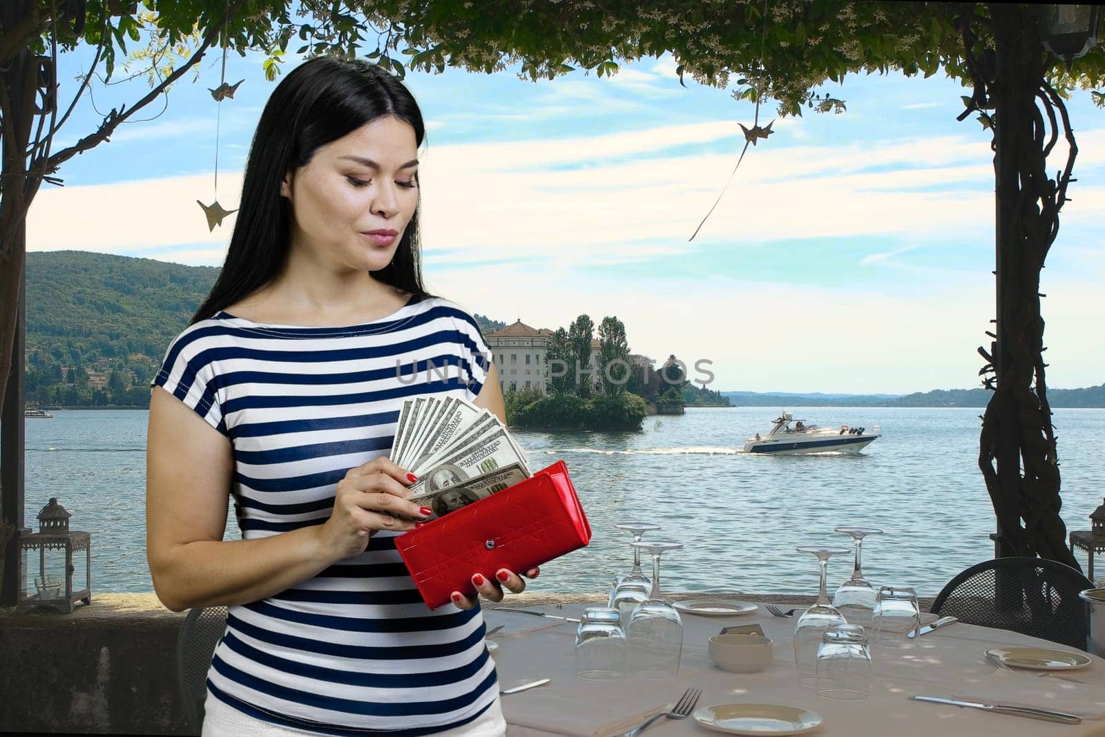 Asian woman is getting dollars from her red wallet on vacation. Summer resort background.